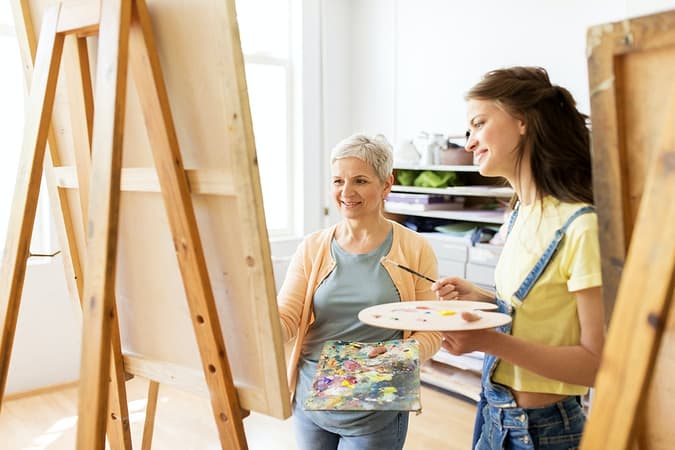women with easels and palettes at art school